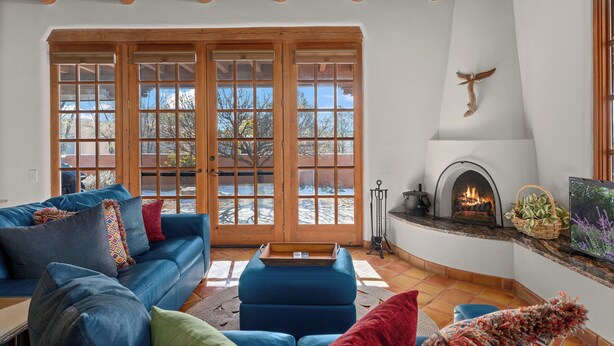A cozy living room with a blue sofa, a fireplace, and large windows. - Quail Run (Santa Fe)