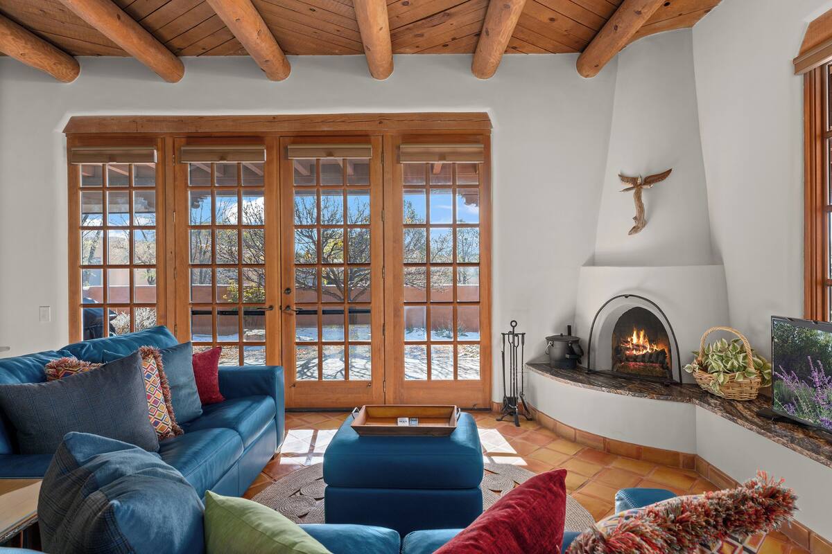A cozy living room with a blue sofa, a fireplace, and large windows.
