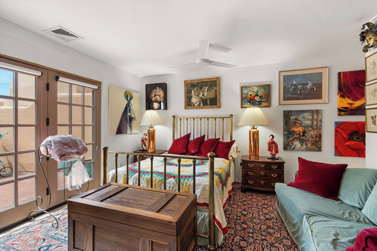 A bedroom with a bed, a dresser, a nightstand, a sofa, and a window.