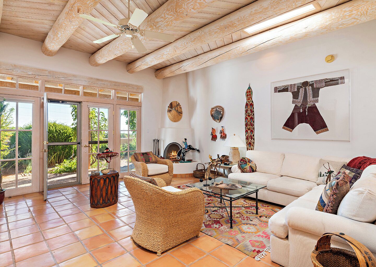 A spacious living room with a high ceiling, a fireplace, and a large window.