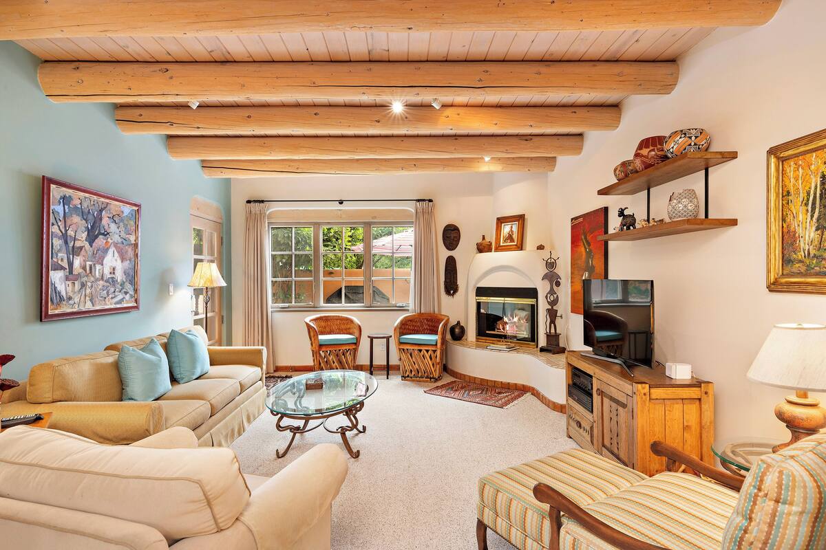 A cozy living room with a sofa, armchairs, a glass coffee table, and a fireplace.