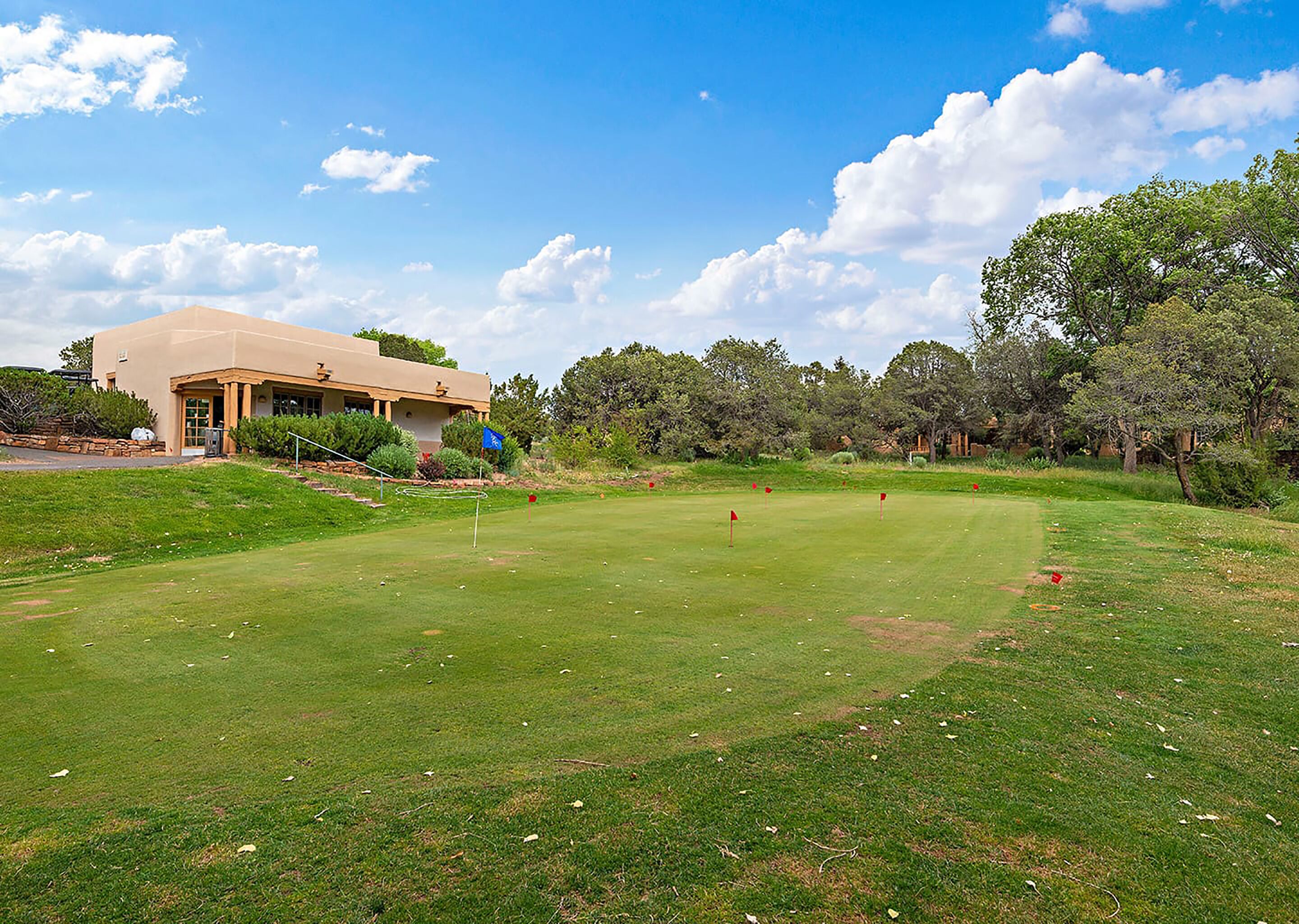 Un campo de golf con un club de campo, césped bien cuidado y árboles al fondo.