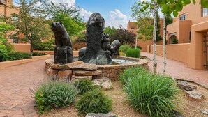 A courtyard with a central fountain, surrounded by brick pathways and greenery. - Quail Run (Santa Fe)