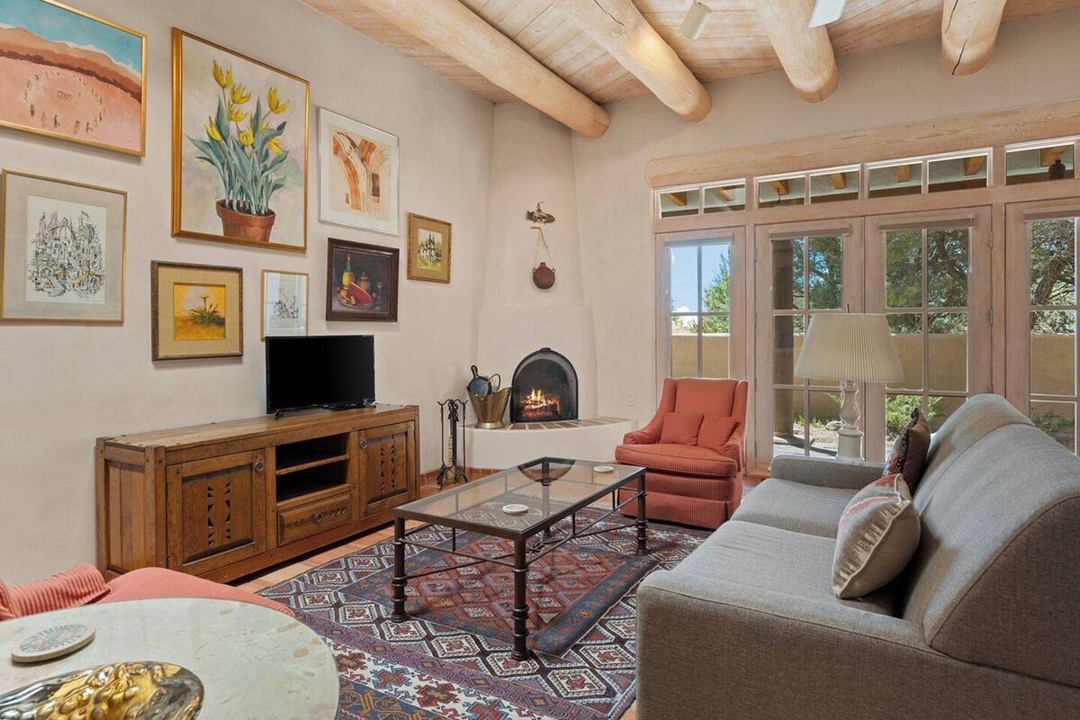 A living room with a fireplace, a television, and various framed artworks on the walls.