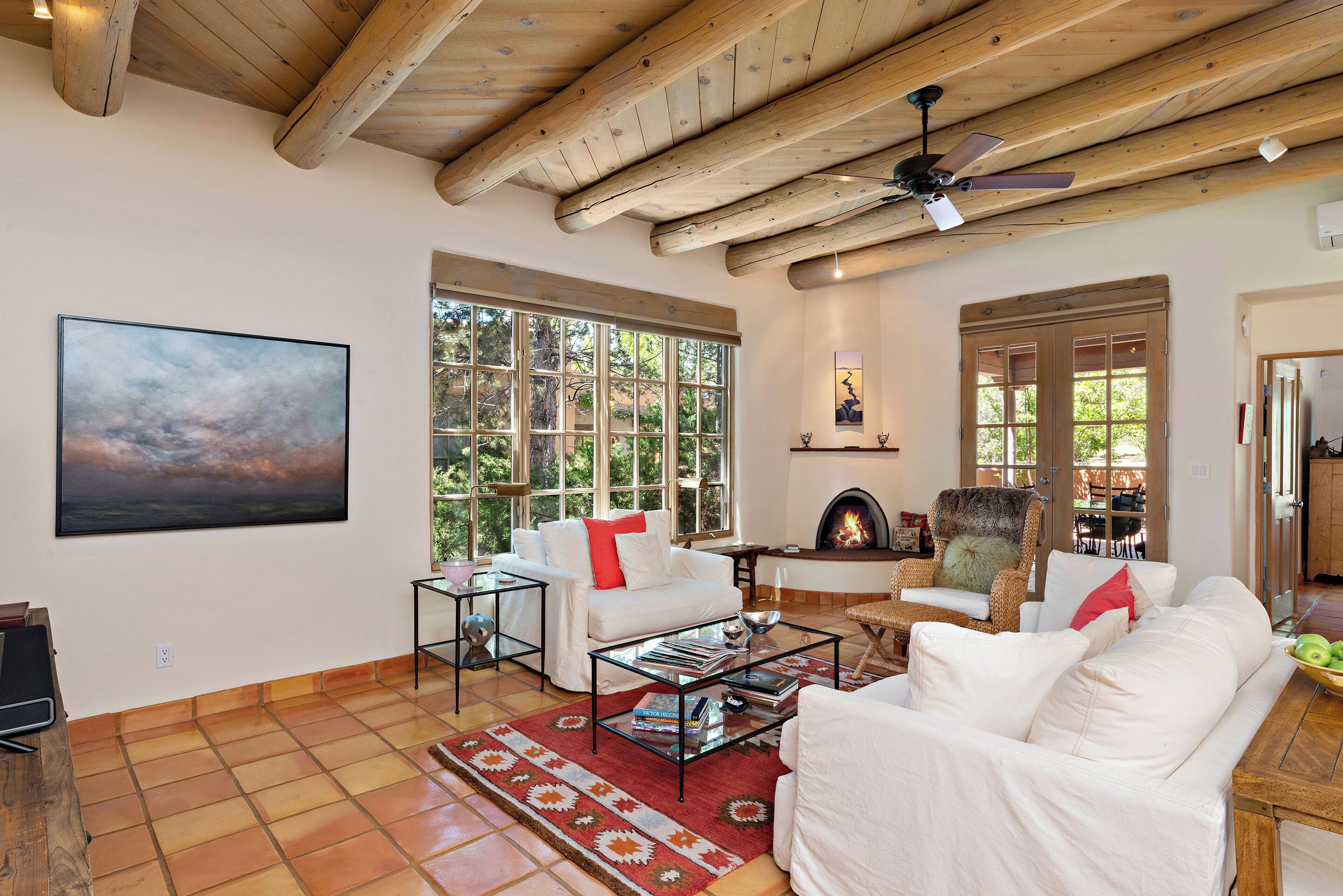 Una sala de estar amplia con chimenea, ventanas grandes y ventilador de techo.