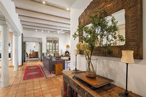 A spacious living area with a fireplace, a large mirror, and a plant on a wooden console table.