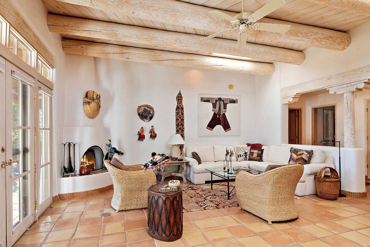 A spacious living room with a fireplace, wicker furniture, and a ceiling fan.