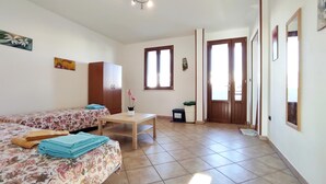 A room with two beds, a table, and a window. - Casa Vacanze Orlando - Con Veranda Vista Mare A 200 M Dal Mare (Castrignano del Capo)