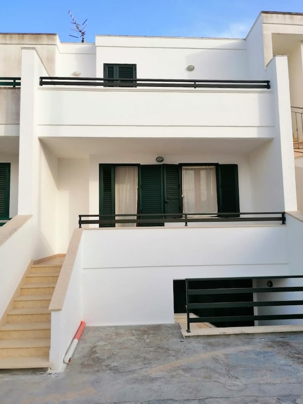A modern two-story building with a flat roof, a balcony on the upper floor, and a staircase leading to the entrance. - Casa Vacanze Orlando - Con Veranda Vista Mare A 200 M Dal Mare (Castrignano del Capo)