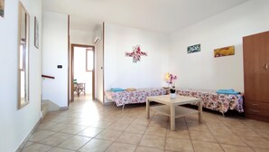 A room with a bed, a table, and a chair. There is a door leading to another room. - Casa Vacanze Orlando - Con Veranda Vista Mare A 200 M Dal Mare (Castrignano del Capo)