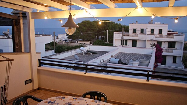 A rooftop terrace with a table and chairs, overlooking a residential area with white buildings and a view of the sea. - Casa Vacanze Orlando - Con Veranda Vista Mare A 200 M Dal Mare (Castrignano del Capo)