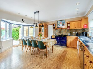 A spacious kitchen with wooden cabinets, a blue stove, and a dining area with green chairs and a table. - Perfect for family and friends get togethers to enjoy coast and countryside. (Walpole St Peter, near King&rsquo;s Lynn)