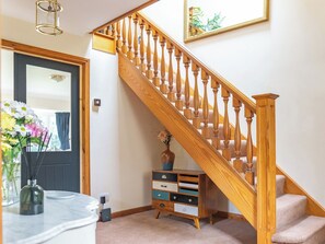 A staircase with wooden balusters and a wooden handrail, leading to a landing with a small wooden cabinet and a vase of flowers. - Perfect for family and friends get togethers to enjoy coast and countryside. (Walpole St Peter, near King&rsquo;s Lynn)