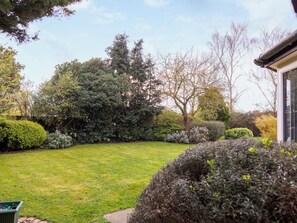 A well-maintained garden with a variety of shrubs and trees, a neatly trimmed lawn, and a pathway leading to a building. - Perfect for family and friends get togethers to enjoy coast and countryside. (Walpole St Peter, near King&rsquo;s Lynn)