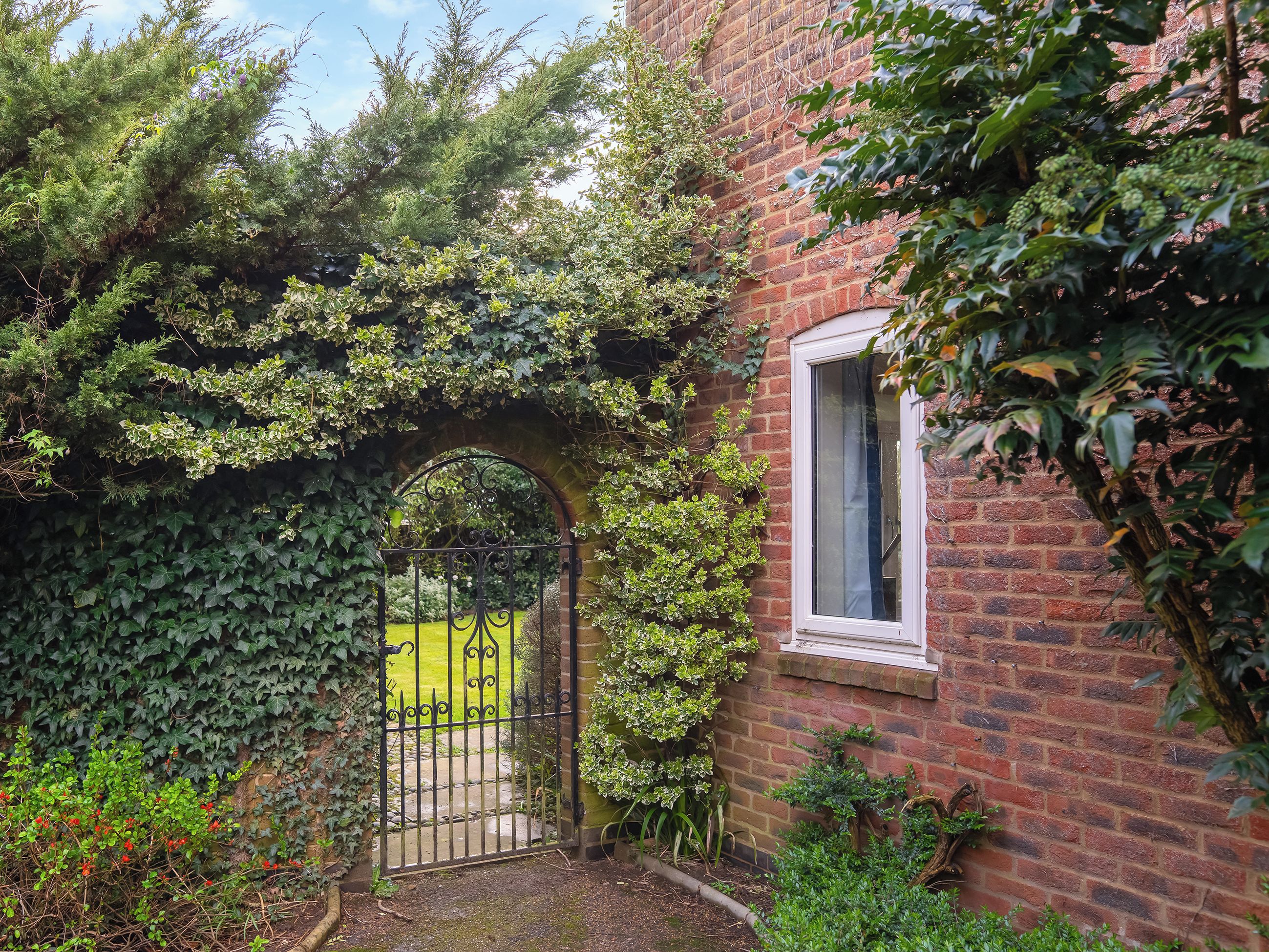 A brick building with a white window and a black iron gate.