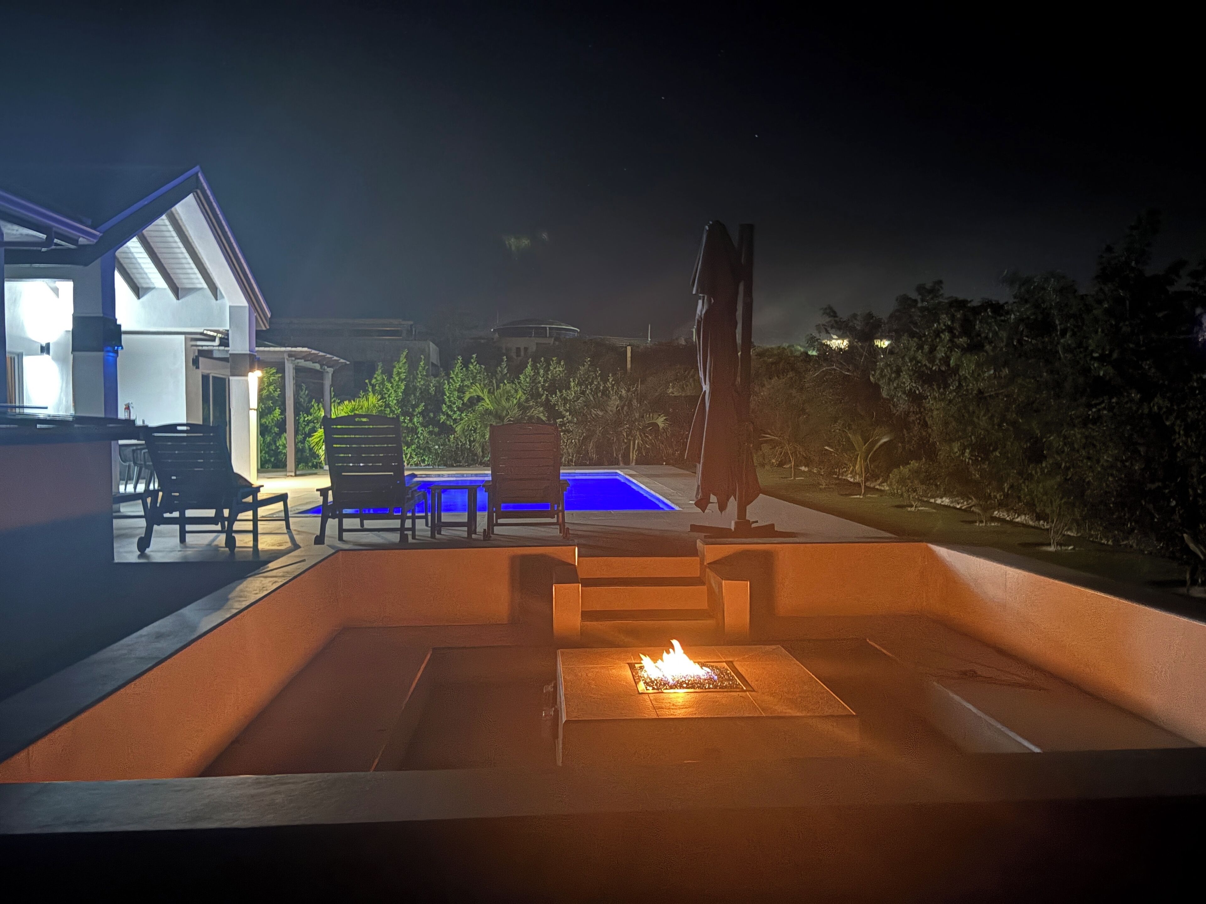 An outdoor patio area with a fire pit, seating, and a swimming pool.