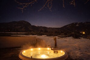 Een jacuzzi omringd door sneeuw, met bergen op de achtergrond.