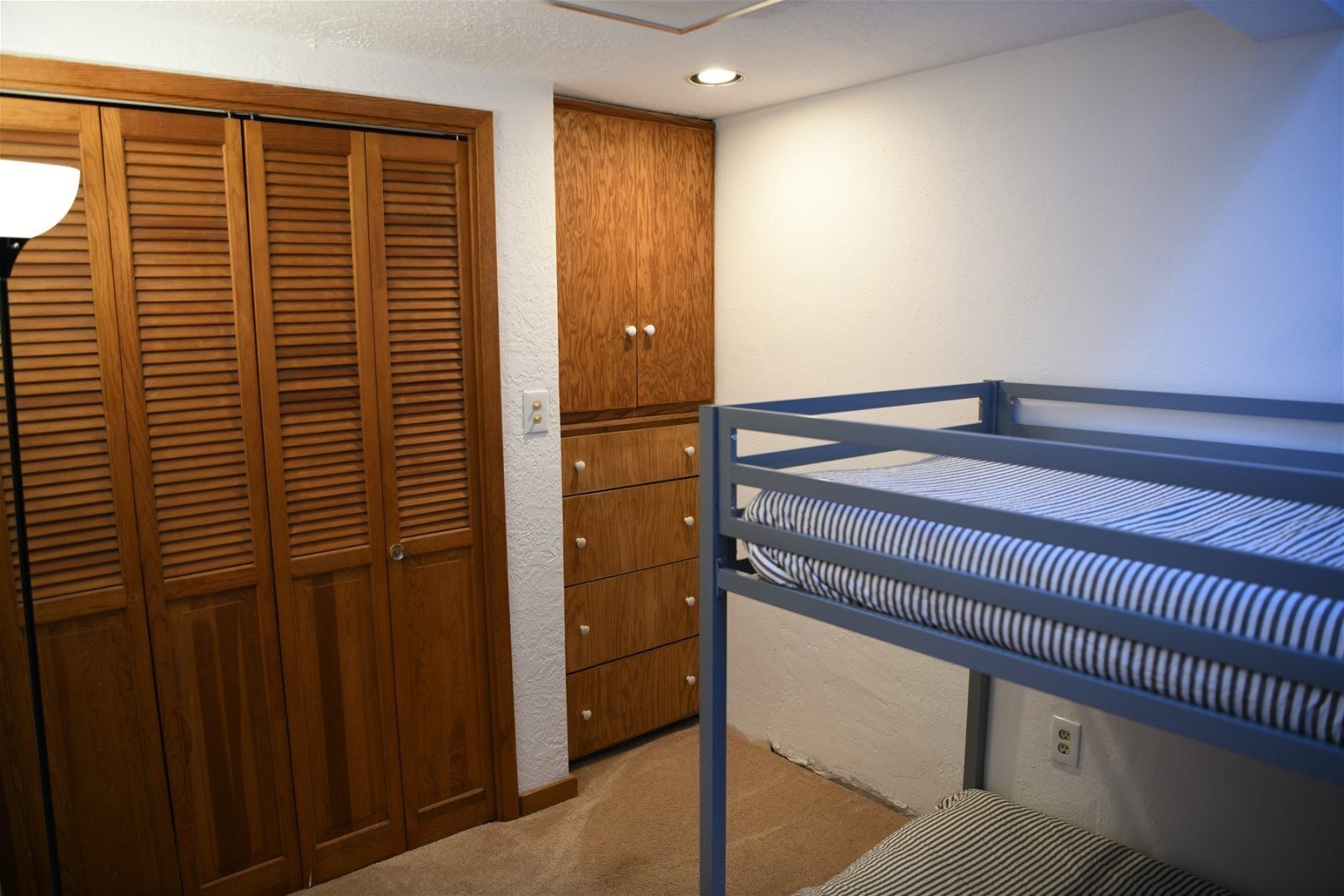 Ein Schlafzimmer mit Etagenbett, Holzschrank und einem kleinen Schminktisch.