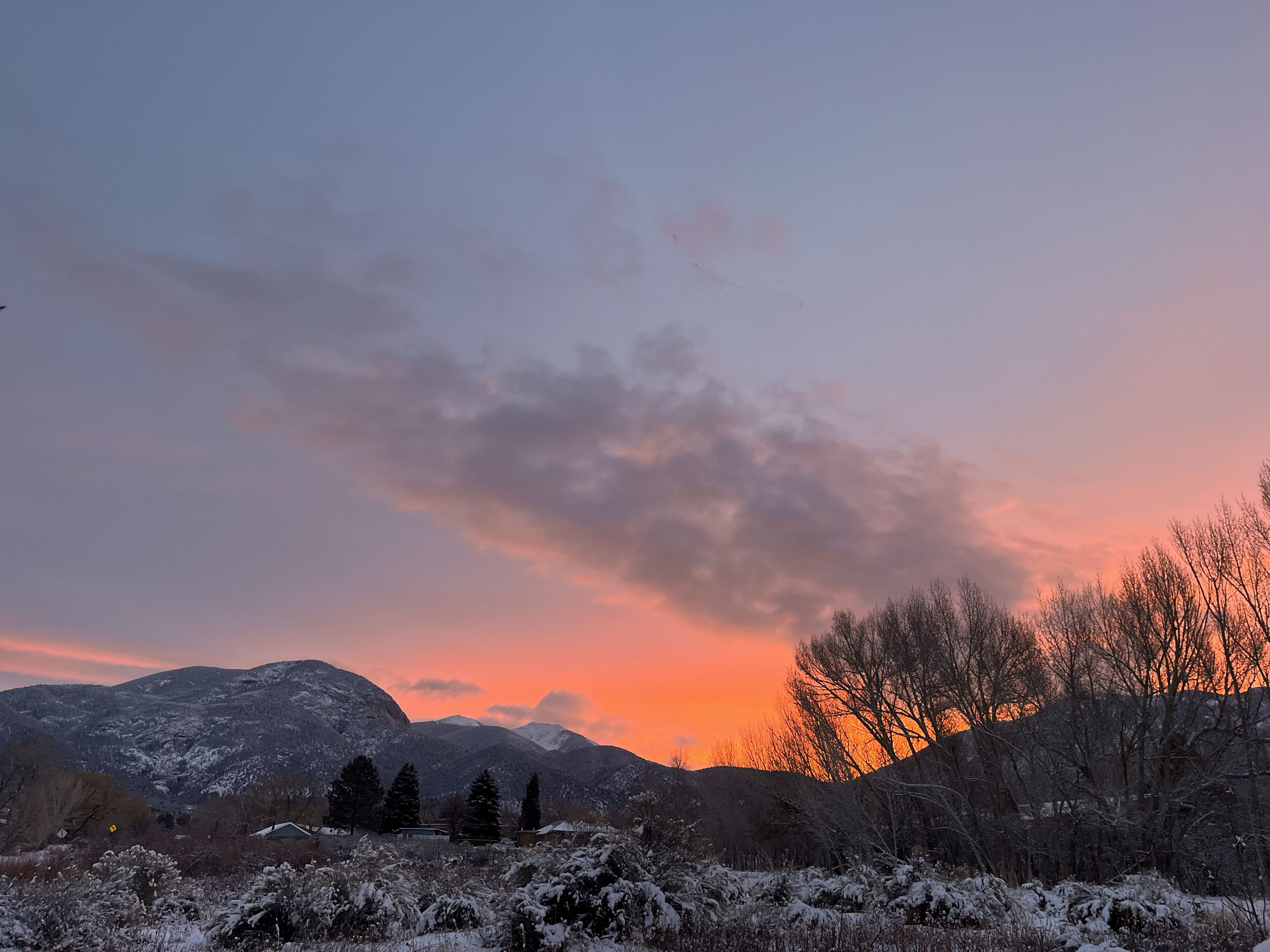 A mountainous landscape with snow-covered trees and a sunset.