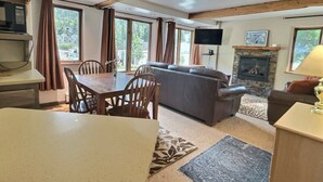 Una sala de estar con chimenea, un sofá y un comedor con sillas y una mesa.