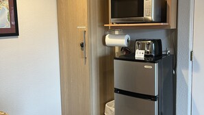 Una cucina compatta con mobili in legno, un frigorifero in acciaio inossidabile, un forno a microonde e un tostapane.