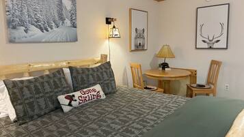Un dormitorio con cama, mesita de noche, lámpara, silla, mesa y decoración en la pared.
