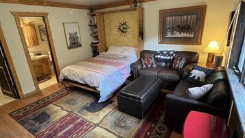 Un espacio habitable compacto con cama, sofá, una mesita y un tapete.