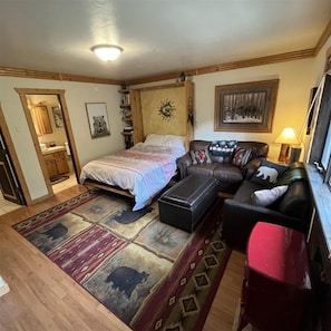 A compact living space with a bed, a sofa, a small table, and a rug. - Backcountry Haven at Taos Ski Valley (Taos Ski Valley)
