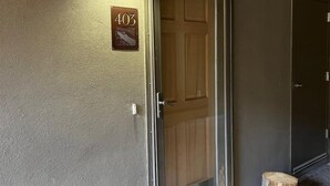 A hallway with a door marked "403", a wooden door, and a small wooden stool. - High Altitude Gem at Taos Ski Valley (Taos Ski Valley)