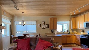 A cozy living room with a brown leather sofa and a dining area with a wooden table and chairs. - High Altitude Gem at Taos Ski Valley (Taos Ski Valley)