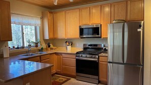 A kitchen with wooden cabinets, a stainless steel refrigerator, a microwave, an oven, and a sink. - High Altitude Gem at Taos Ski Valley (Taos Ski Valley)