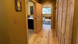 A wooden hallway with a door leading to a bathroom and a bedroom. - Cozy Amizette - Cabin (Taos Ski Valley)