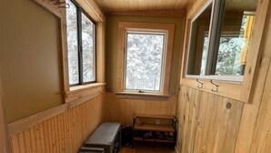 A narrow wooden room with a bench, a small table, and a window with a view of trees. - Cozy Amizette - Cabin (Taos Ski Valley)