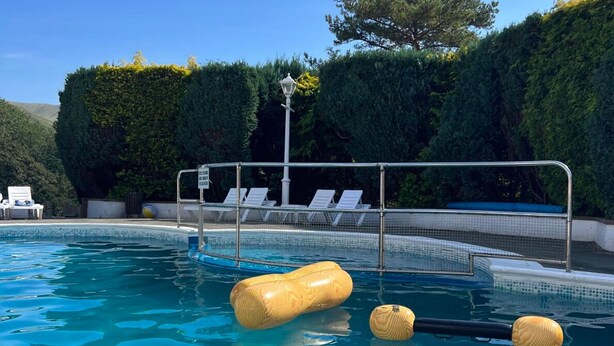 Una piscina con sillas de descanso y un puesto de socorrista.