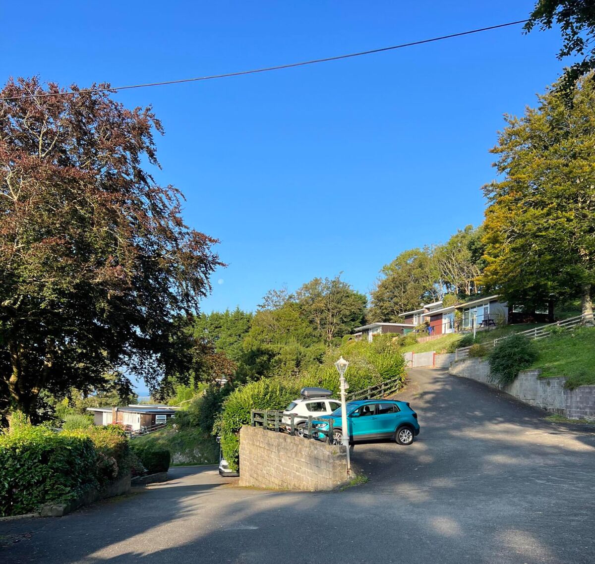 A residential street with houses, a parked car, and a lamp post.