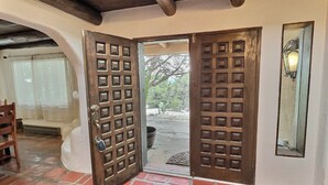 A room with a wooden door, a bench, and a tiled floor. - Beautiful Adobe in the Pines Above Taos (Taos)