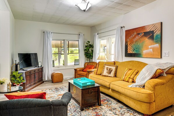 A living room with a sofa, a television, a coffee table, and a plant. - Lakeview Vacation Rental - Walk to Crystal Lake! (Lakeview)