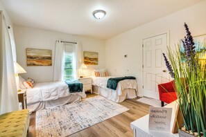A bedroom with two beds, a nightstand, a lamp, a rug, and a door. - Lakeview Vacation Rental - Walk to Crystal Lake! (Lakeview)