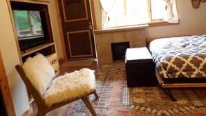 Une pièce confortable avec un lit, une télévision, une cheminée et un tapis à motifs.