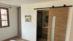 A bedroom with a bed, a sliding door closet, a painting, and a window. - A 10 mn des Plages, Appartement Refait à Neuf au Cœur D'un Village Authentique (Monacia-d'Aullène)