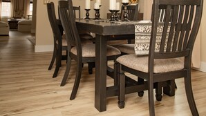 A dining room with a dark wooden table, matching chairs, and a unique antler chandelier.