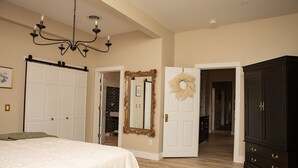 A bedroom with a large bed, a chandelier, a wardrobe, and a mirror with a wreath.