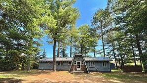 A cabin with a front porch, surrounded by tall trees. - Cozy 3 b/r home w/ quick access to snowmobile trails in the beautiful Northwoods (Minocqua)