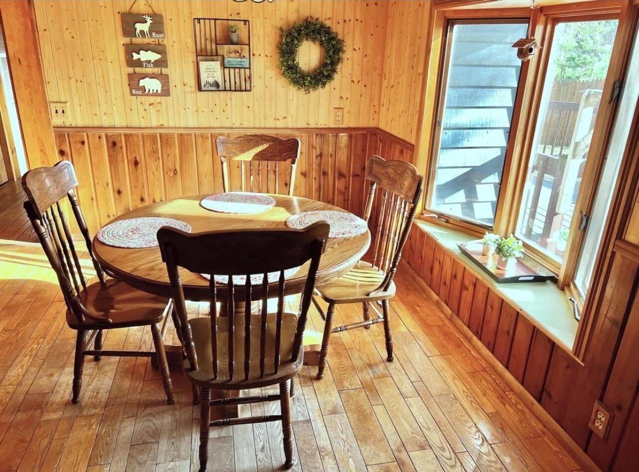A wooden dining room with a round table and four chairs.