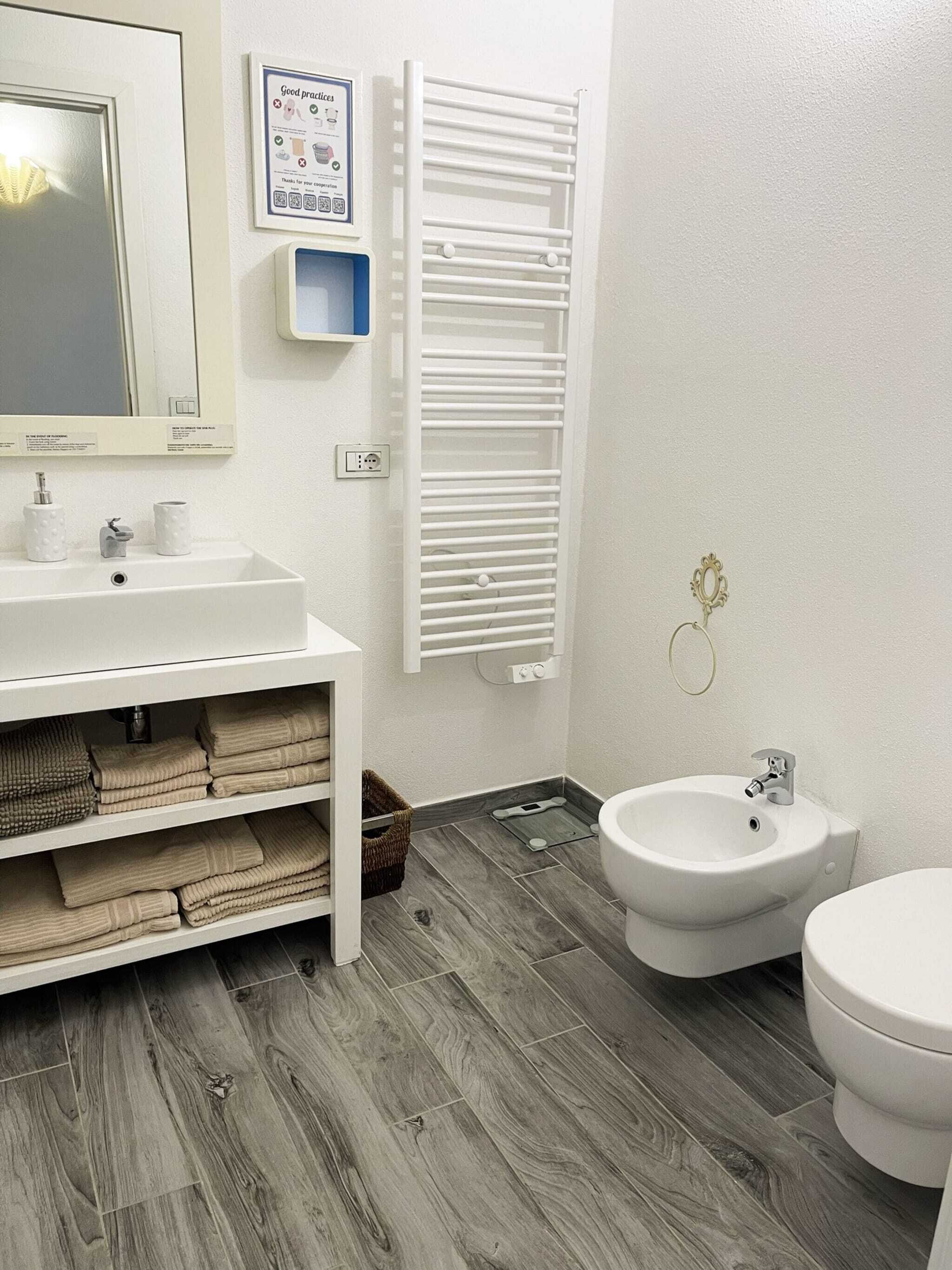 Un baño con lavamanos blanco, un bidé y un espejo.