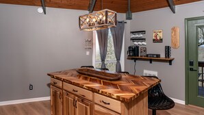 Una cocina con isla de madera, barra de café y lámpara colgante.