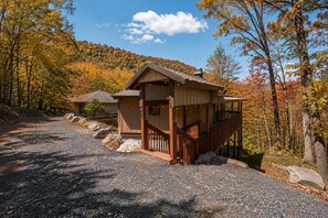 A lodge with a wooden exterior, a covered porch, and a gravel driveway.