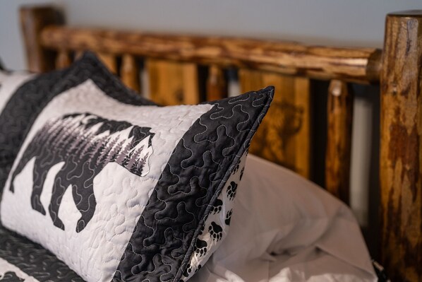Una cama con un almohadón acolchado que presenta un estampado animal en blanco y negro.