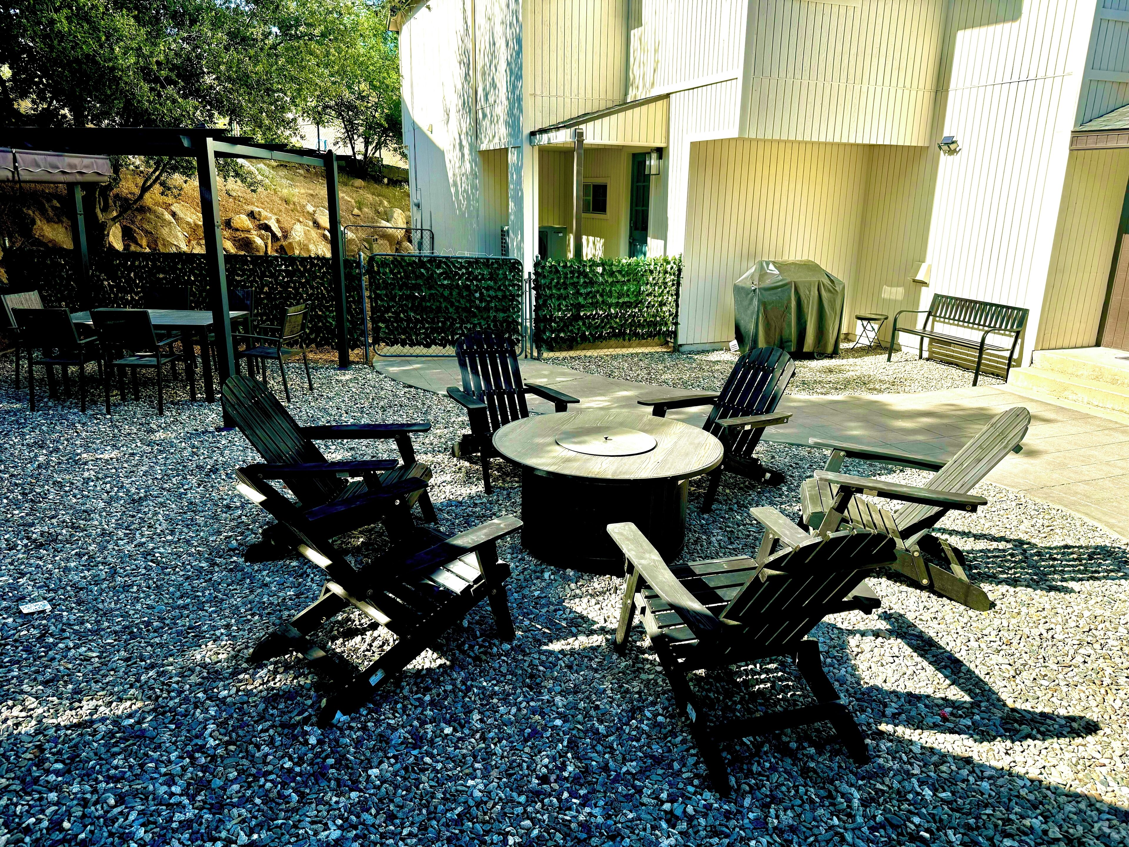 Un espace extérieur aménagé avec une table ronde et quatre chaises Adirondack, le tout entouré de gravier.