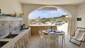 A small, clean kitchen with a view of a hill and a castle.